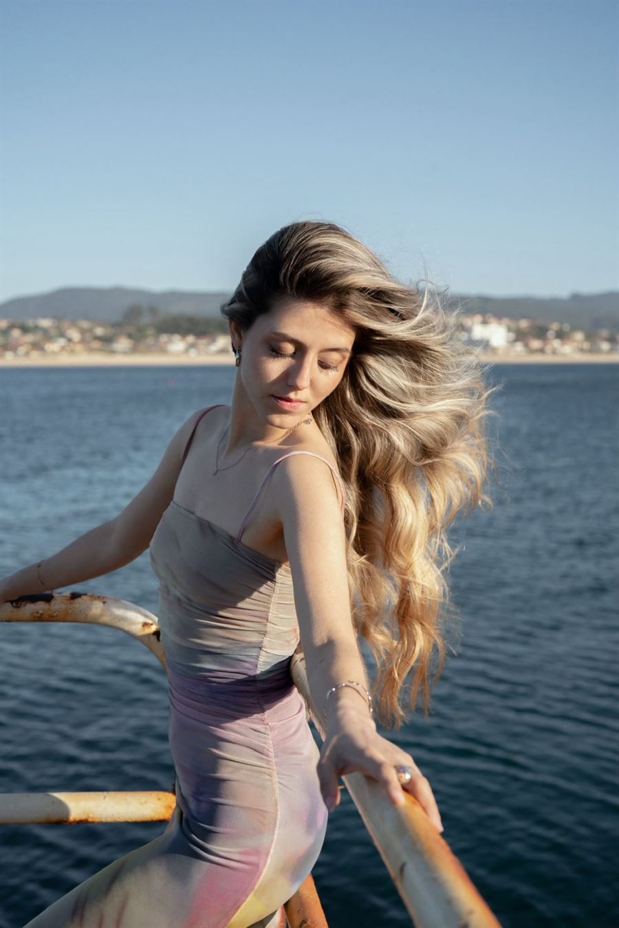 Melena rubia con ondas movidas por el viento junto al mar